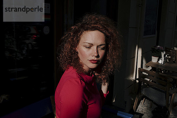 Porträt einer rothaarigen Frau in einem Cafe  die zur Seite schaut