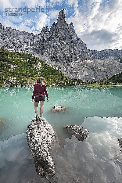 Junge Frau  Wanderer stehend auf Felsen im Wasser am türkisgrünen Sorapis See  Lago di Sorapis  Berggipfel Dito di Dio  Dolomiten  Belluno  Italien  Europa