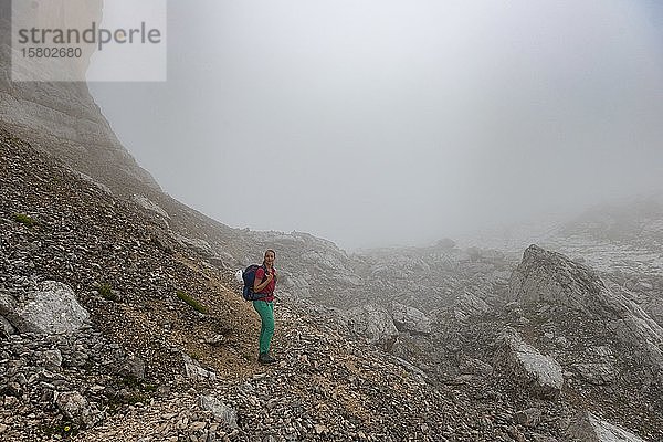 Junge Frau  Wanderung in einem Geröllfeld im Nebel in den Bergen  schlechte Sicht  Umrundung von Sorapiss  Dolomiten  Belluno  Italien  Europa