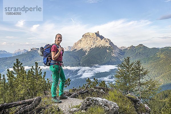 Junge Frau  Wanderin blickt in die Kamera  hinten Berggipfel La Rocheta  Dolomiten  Belluno  Italien  Europa