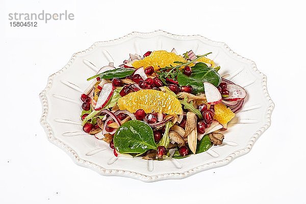 Servierter Salat auf einem Porzellanteller mit Orangenscheiben  Granatapfel  Rucola und Austernpilzen  weißer Hintergrund  Lebensmittel  Russland  Europa