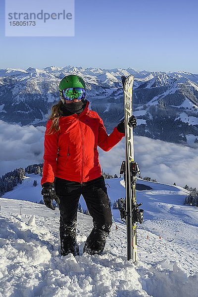 Skifahrer mit Skihelm und Skiern an der Skipiste stehend  in die Kamera schauend  Bergpanorama im Hintergrund  SkiWelt Wilder Kaiser  Brixen im Thale  Tirol  Österreich  Europa