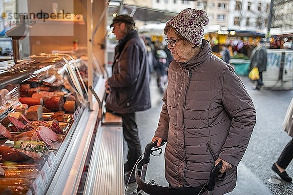 Seniorin schaut sich die Wurstwaren eines Metzgers auf dem Wochenmarkt an  Köln  Nordrhein-Westfalen  Deutschland  Europa