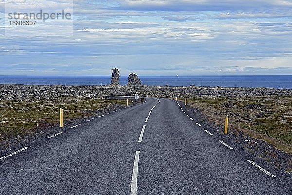 Landstraße führt zu zwei bizarren Felsnadeln  Lóndrangar  Snaefellsness-Halbinsel  Island  Europa