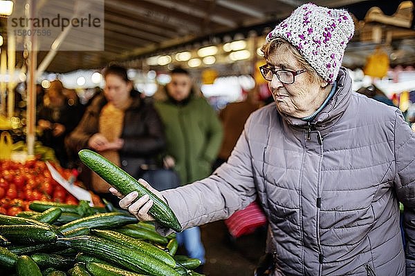 Seniorin inspiziert Gurken auf dem Wochenmarkt  Köln  Nordrhein-Westfalen  Deutschland  Europa