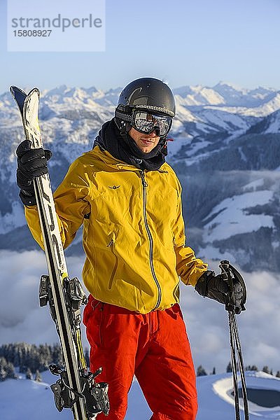 Skifahrer vor Bergpanorama  hält Ski  Blick in Kamera  Gipfel Hohe Salve  SkiWelt Wilder Kaiser Brixenthal  Hochbrixen  Tirol  Österreich  Europa
