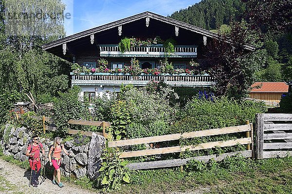 Wanderer vor einem Bauernhaus oberhalb von Sachrang  Chiemgau  Oberbayern  Bayern  Deutschland  Europa