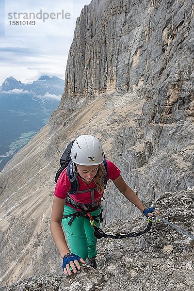 Junge Frau  mit einem Stahlseil gesicherte Wanderin beim Klettern an einer Felswand  Klettersteig Francesco Berti  Sorapiss-Rundweg  Dolomiten  Belluno  Italien  Europa