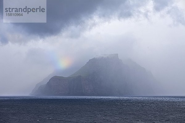 Die Färöer-Insel Kalsoy im Atlantik mit einem kleinen Stück eines Regenbogens  Nebel und Wolken  Färöer-Inseln  Føroyar  Dänemark  Europa