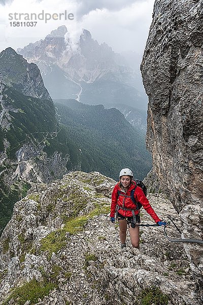 Junge Frau  Wanderin auf dem Klettersteig Vandelli  Sorapiss-Rundweg  Berge mit niedrigen Wolken  Dolomiten  Belluno  Italien  Europa