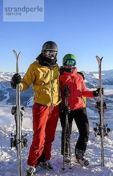 Zwei Skifahrer mit Skihelmen und Skiern stehen auf der Skipiste vor einem Bergpanorama  Paar  Blick in die Kamera  SkiWelt Wilder Kaiser  Brixen im Thale  Tirol  Österreich  Europa