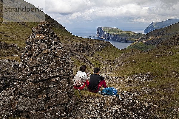 Zwei Wanderer machen eine Pause mit Blick auf den Atlantik  Wanderweg von Tjørnuvík nach Saksun  Streymoy  Färöer Inseln  Føroyar  Dänemark  Europa