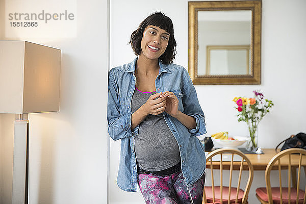 Porträt lächelnde schwangere Frau im Esszimmer