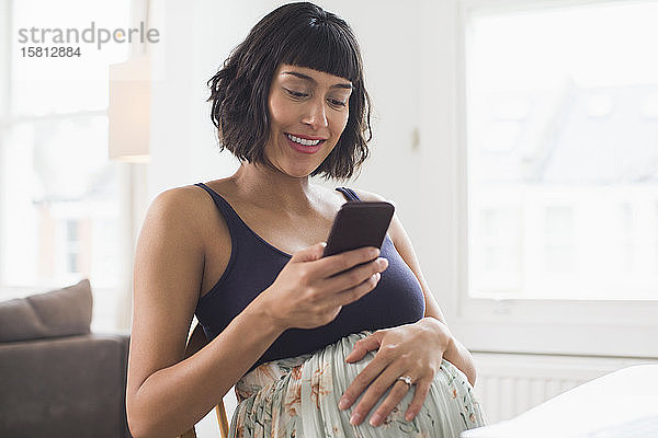 Glückliche schwangere Frau mit Smartphone