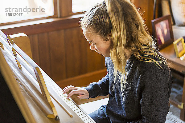 Mädchen im Teenageralter  spielt Klavier und übt.