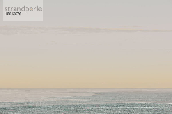 Blick auf ruhiges Ozeanwasser  Horizont und Himmel in der Morgendämmerung