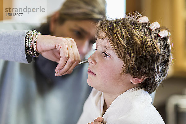 Ein sechsjähriger Junge  der sich zu Hause von seiner Mutter die Haare schneiden lässt