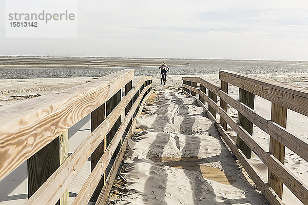 Teenagerin auf dem Fahrrad über die Brücke zum Strand