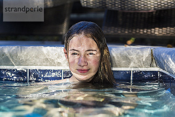 Ein dreizehnjähriges Teenagermädchen in einem Schwimmbad mit reflektiertem Licht  das auf ihrem Gesicht spielt