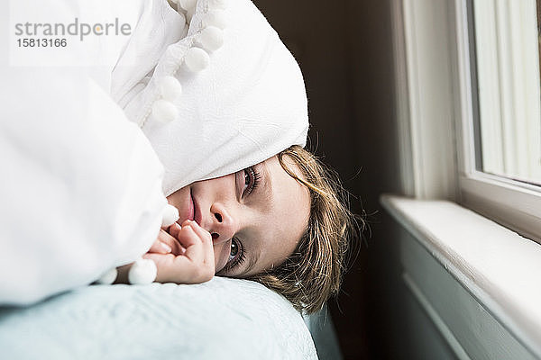 Ein sechsjähriger Junge im Bett mit Decken über dem Kopf