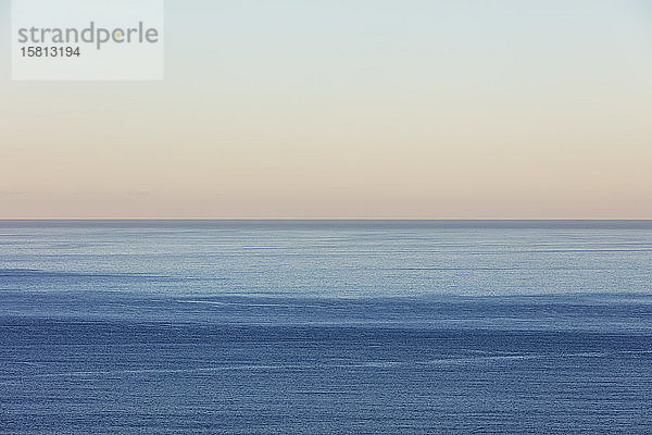 Blick auf ruhiges Ozeanwasser  Horizont und Himmel in der Morgendämmerung