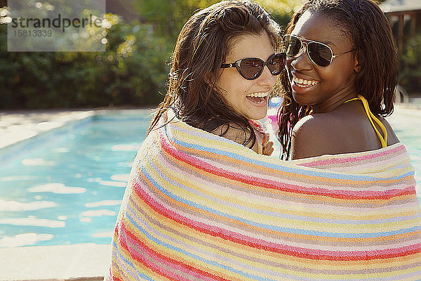 Porträt glückliche Teenager-Freundinnen im Handtuch eingewickelt am Sommerpool