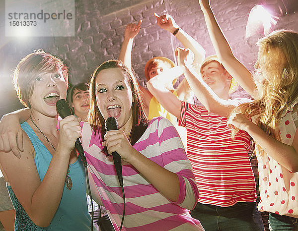 Glückliche Teenager-Freunde singen Karaoke auf einer Party