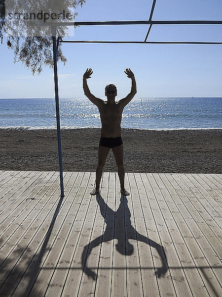 Silhouette und Schatten eines Mannes  der sich auf einem sonnigen Stranddeck ausstreckt  Kreta  Griechenland