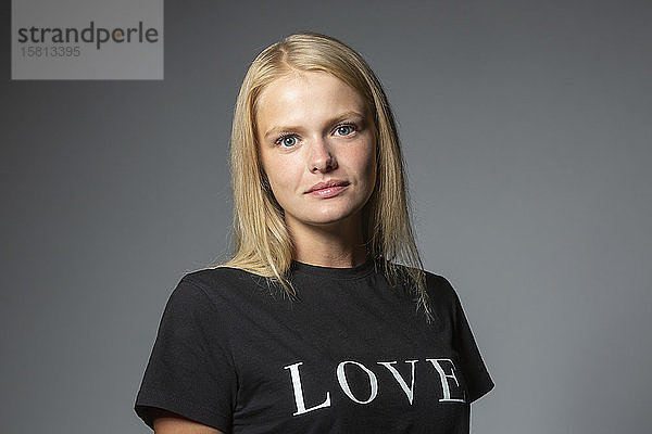 Porträt zuversichtlich  junge Frau in der Liebe T-Shirt auf grauem Hintergrund