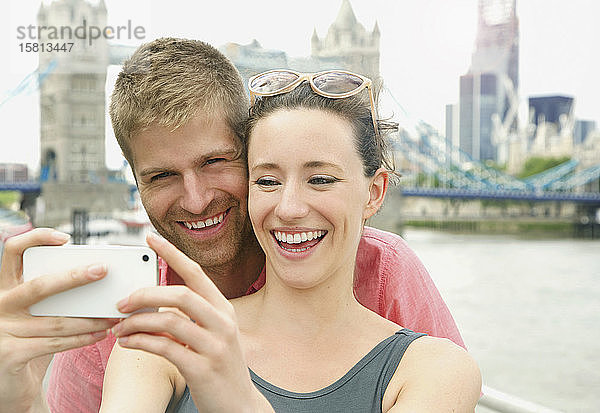 Glückliches Paar macht Selfie mit Fotohandy vor der Tower Bridge  London  UK
