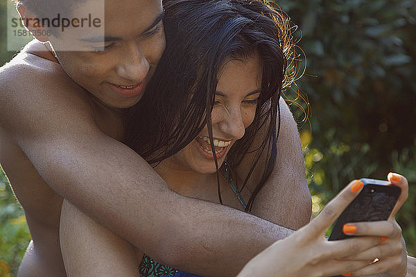 Zärtliches Teenager-Paar mit Smartphone