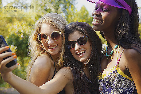 Glückliche Teenager-Freundinnen nehmen Selfie mit Smartphone auf sonnigen Terrasse