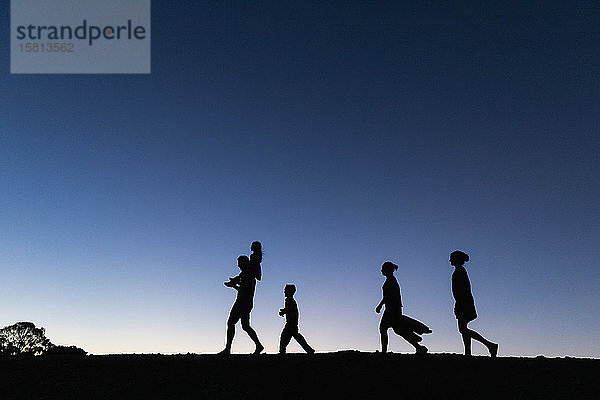 Silhouette Familie zu Fuß gegen blauen Himmel in der Abenddämmerung
