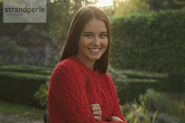 Porträt lächelnd Teenager-Mädchen in roten Pullover im Herbst Park
