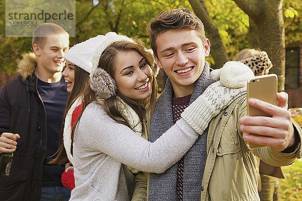 Glückliches jugendliches Paar  das ein Selfie im Herbstpark macht