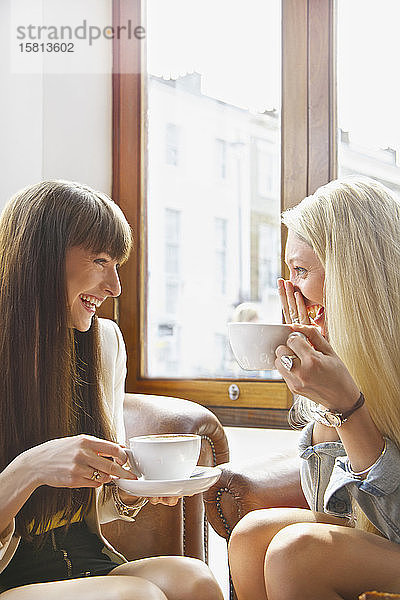 Glückliche junge Frauen trinken Kaffee in einem Caféfenster