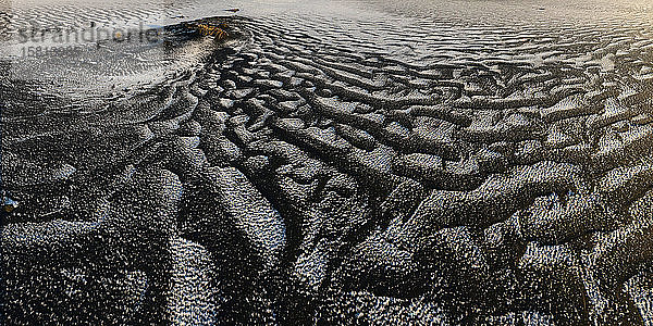 Windgepeitschter schwarzer Sand mit Schnee auf der Oberfläche  Island  Polarregionen