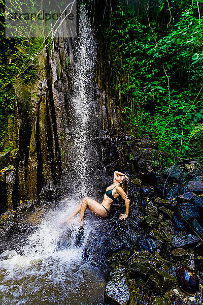Frau posiert für ein Foto unter einem Wasserfall am Beji Guwang Hidden Canyon  Bali  Indonesien  Südostasien  Asien