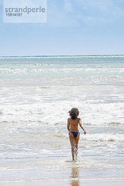 Eine junge Frau läuft in den tropischen Atlantik  Insel Morro de Sao Paulo  Bahia  Brasilien  Südamerika