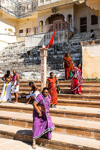 Frauen in farbenfrohen Saris gehen barfuß die Ghats (Stufen) zum heiligen Wasser des Pushkar-Sees hinunter  Pushkar  Rajasthan  Indien  Asien