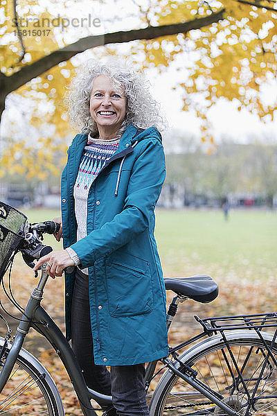 Porträt lächelnd  zuversichtlich ältere Frau Fahrradfahren im Herbst Park