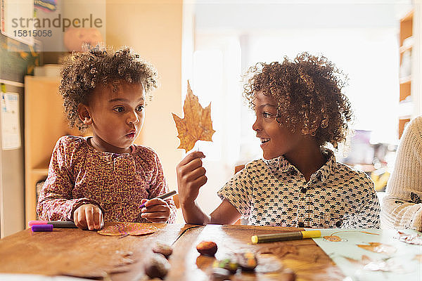 Bruder und Schwester basteln am Tisch für den Herbst