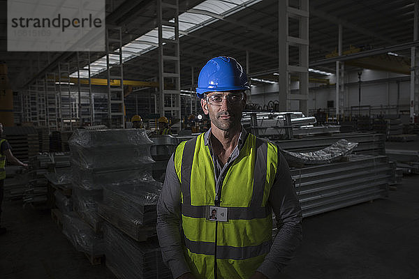 Porträt eines selbstbewussten  ernsten Arbeiters in einer dunklen Stahlfabrik