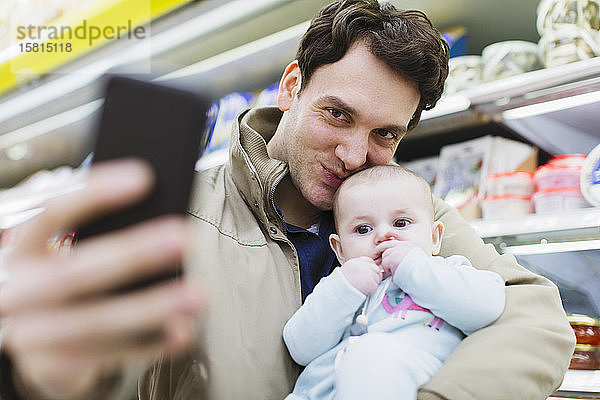 Zärtlicher Vater und kleine Tochter machen ein Selfie im Supermarkt