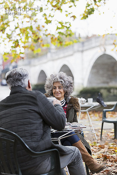 Lächelndes aktives Seniorenpaar genießt Kaffee im Herbstparkcafé