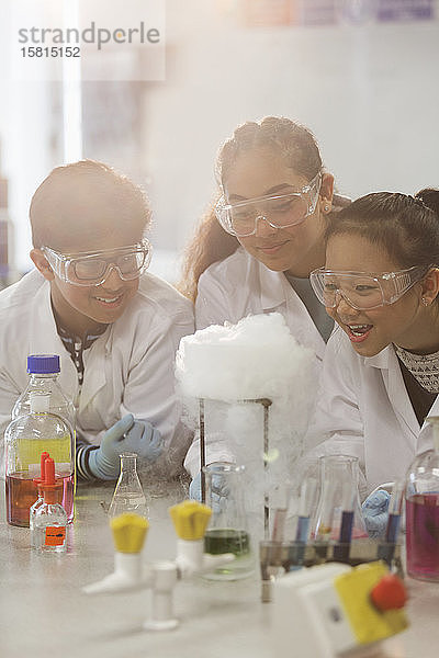Überrumpelte Schüler  die ein wissenschaftliches Experiment durchführen und eine chemische Reaktion im Klassenlabor beobachten