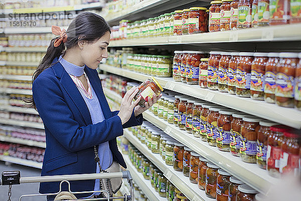 Frau liest Etikett auf Glas im Supermarkt