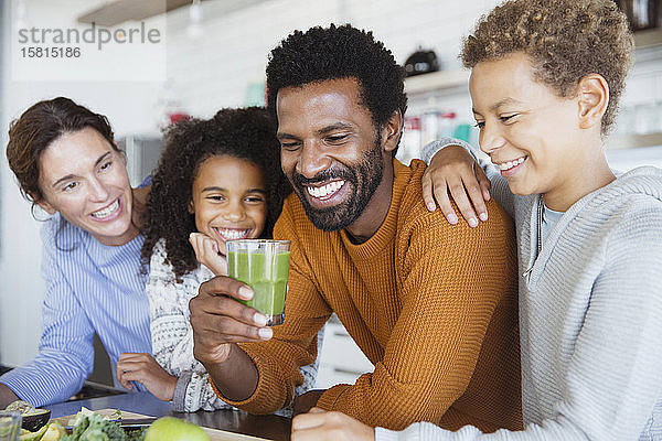 Multiethnische Familie trinkt gesunden grünen Smoothie in der Küche