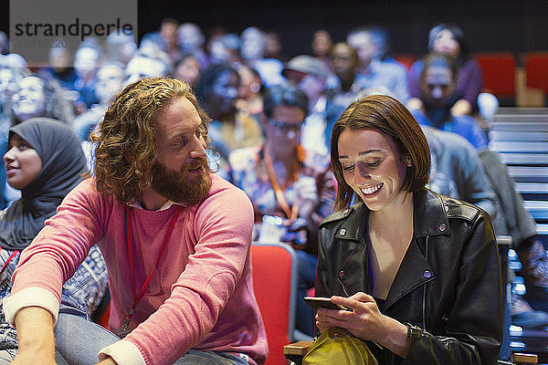 Mann und Frau mit Smartphone im Konferenzsaal