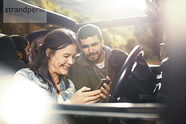 Junges Paar überprüft GPS auf dem Smartphone und genießt die Fahrt im Jeep